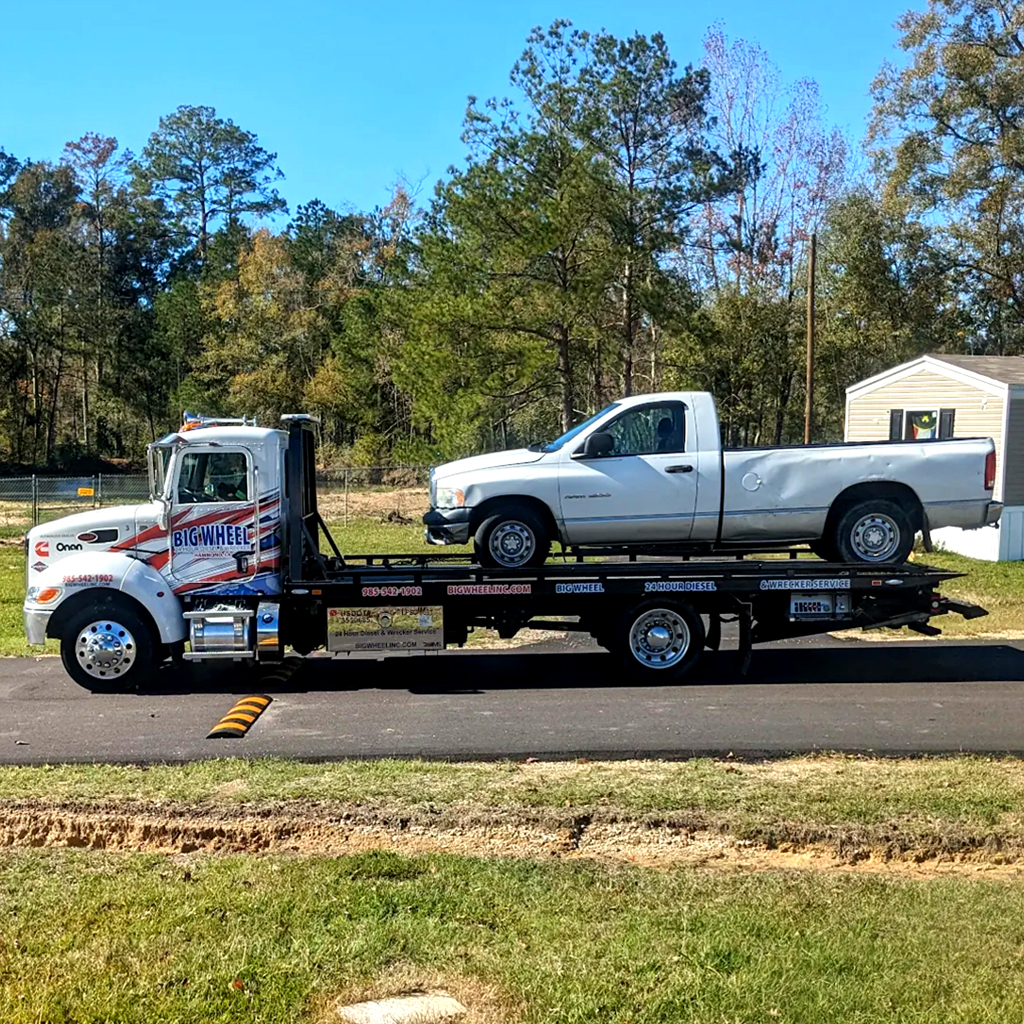 photo of Big Wheel Wrecker Service flat bed truck with pickup truck on back showing light towing